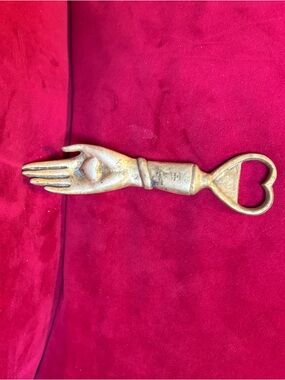 Heavy brass hand- shaped bottle opener with heart shaped on palm.